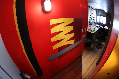 Wide fisheye view down a hallway inside an early Blacklist shop with red walls and a deck display