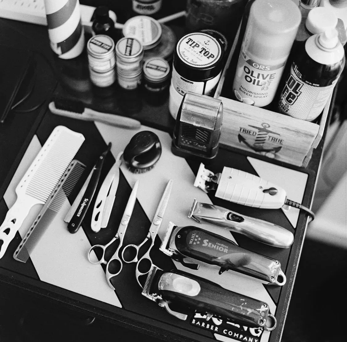 A barber's tray of combs, razors, clippers, and grooming products laid out on the station
